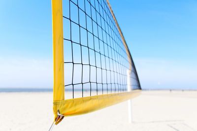 Volleyball net at beach against blue sky