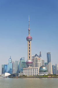 Communications tower in city against clear sky