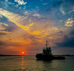 Silhouette ship in sea against sky during sunset