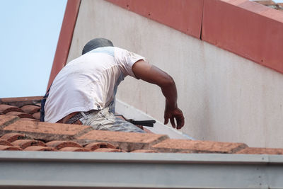 Low angle view of man relaxing on wall