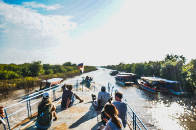 People on boat in river against sky