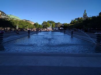 People in swimming pool against clear blue sky