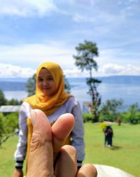 Happy woman holding umbrella against sky