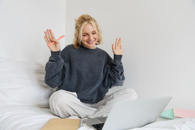 Portrait of young woman sitting on bed at home