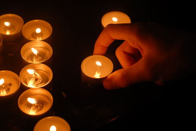 Cropped hand holding illuminated candle