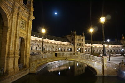 Illuminated bridge over canal in city at night