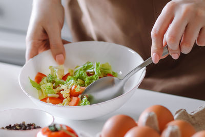 Woman mixes vegetable salad in bowl. home cooking for healthy diet.