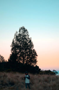 Man on field against clear sky during sunset