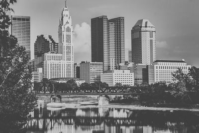 Modern buildings by river against sky in city