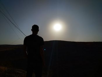 Rear view of silhouette man standing against sky during sunset