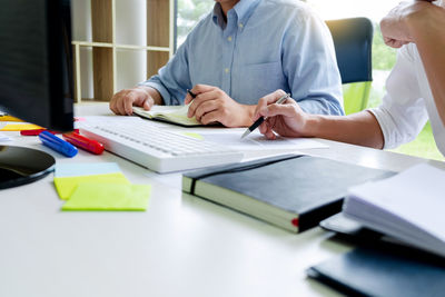 Rear view of man and woman using laptop on table