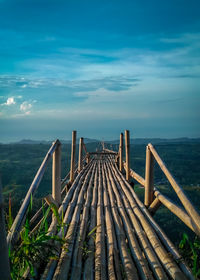 Wooden bridge over sea against sky