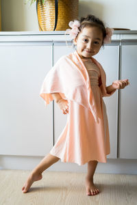 A little girl is standing in a beautiful dress with hair accessories. pretend play at home.