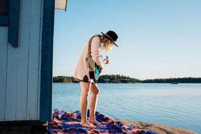 Woman stood playing the guitar on a rock at the beach on a summers day