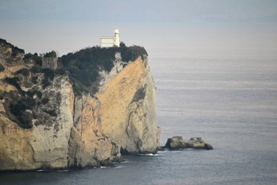 Rocks on beach by sea against sky