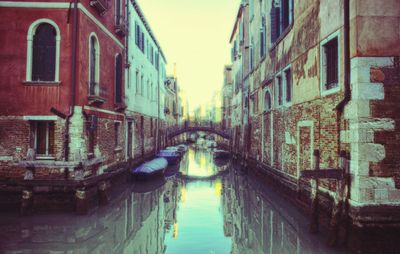 Canal amidst buildings against sky