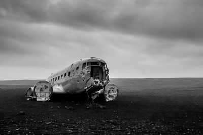 Airplane wreckage at solheimasandur beach against cloudy sky