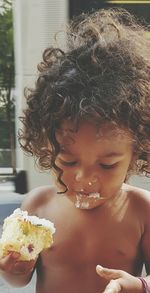 Close-up of shirtless boy eating cake