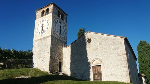 Low angle view of clock tower against clear blue sky