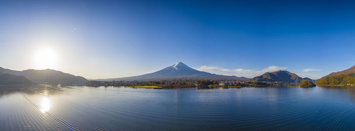 Scenic view of lake by mountains against clear blue sky