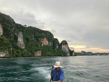 Portrait of boy on rock by sea against sky