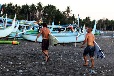 Rear view of shirtless men on boat at beach