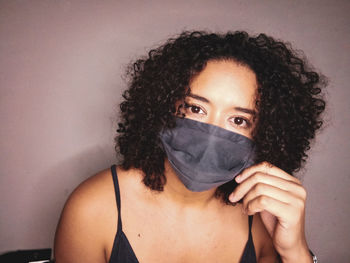 Portrait of beautiful young woman covering face against wall