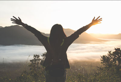 Low angle view of woman standing on field against sky during sunset