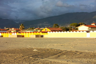 Beach by illuminated buildings against sky