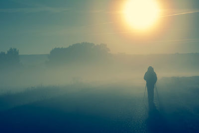 Rear view of silhouette man standing on landscape during sunset