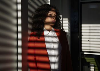 Sunlight on thoughtful businesswoman leaning on wall at office
