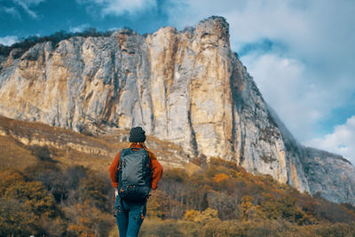 Rear view of man standing on rock against mountain