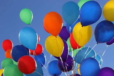 Low angle view of multi colored balloons against clear sky