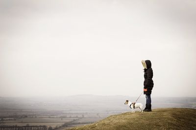 Woman with pet dog overlooking countryside landscape