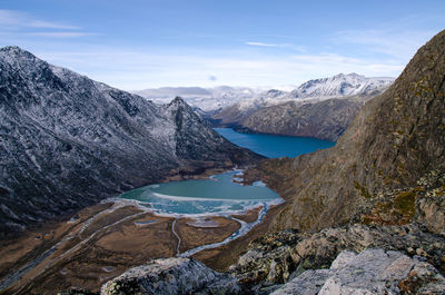 Scenic view of turquoise river flowing into the gjende lake between two snowcapped mountains