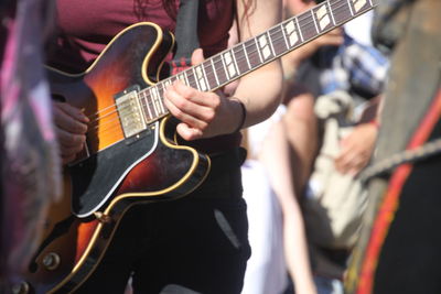 Midsection of woman playing guitar in city