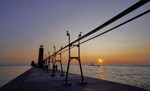 Pier over sea against sky during sunset