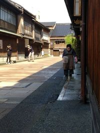 People walking on street amidst buildings in city