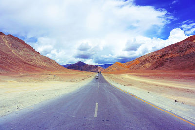 Road amidst mountains against cloudy sky