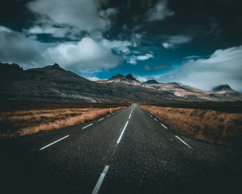 Road leading towards mountains against sky