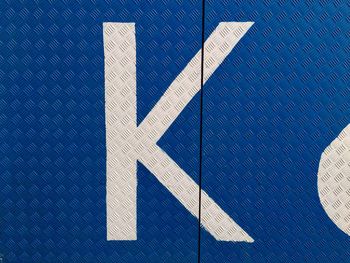 Close-up of alphabet k on blue diamond plate