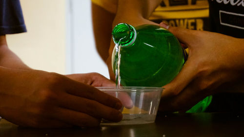 Close-up of hand holding drink bottle on table