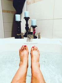 Low section of woman relaxing in bathtub