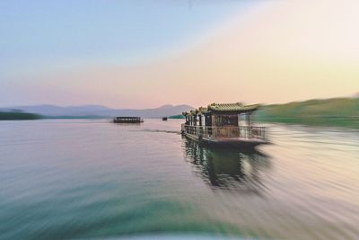 Boat moored in lake against sky during sunset