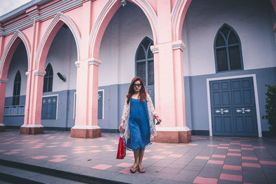 Portrait of young woman standing against building