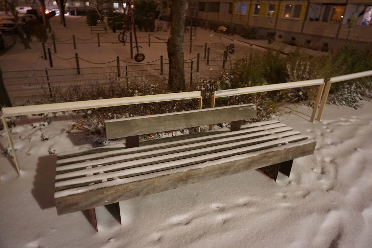 HIGH ANGLE VIEW OF BENCH IN PARK DURING WINTER IN CITY