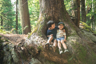 Two young boy friends embrace happily under large tree
