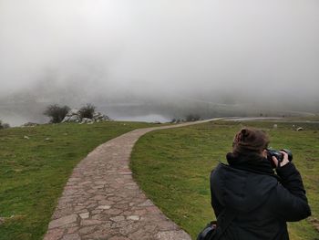 Rear view of woman photographing in foggy weather