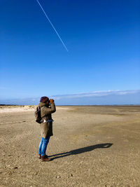 Full length of man standing against blue sky