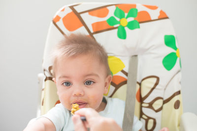 Cropped hand of person feeding food to cute boy at home